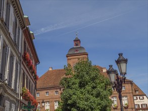 Historic building on the market square surrounded by trees and lanterns under a blue sky,