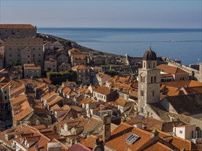 Overview of a historic town with red tiled roofs and a church tower by the sea, dubrovnik,