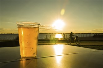 Plastic glass of cold beer on table at sunset on Guaíba waterfront