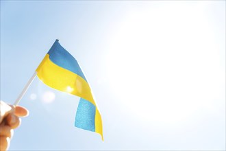 Human hand holding large bicolor yellow blue Ukrainian state flag, national symbol fluttering,