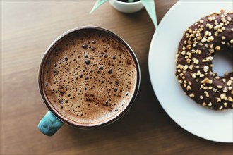 Donuts on the white plate and coffee on the wooden table.