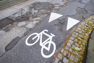 A cycle path pictogram on a road with potholes in Mönchengladbach, Germany, Europe