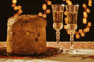 Italian panettone and sparkling wine over a table with Christmas lights on background