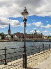 Cityscape with a decorative lantern in the foreground, and impressive historical buildings along a