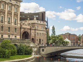 Magnificent historic building on a river with a bridge underneath, under a slightly cloudy sky,