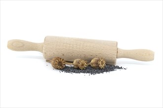 Dried poppy pods and poppy seeds in front of the rolling pin isolated on white background, full