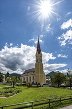 Church at Schliersee in Bavaria Germany with sun and blue sky in front of wooded mountains