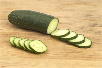 Fresh homegrown cucumber and cucumber slices on a wooden cutting board