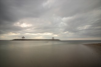 Beautiful seascape in the morning. Tropical sandy beach with breakwater and reflection of the sky
