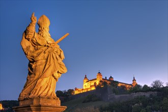 Figure of a saint on the Old Main Bridge with a view of Marienberg Fortress, Wuerzburg, Lower