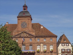 Building with historic façade, a clock and shutters under a clear sky, Weissenburg, Alsace, France,