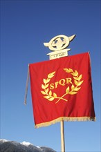 Roman Standard displaying SPQR, against blue sky and alps