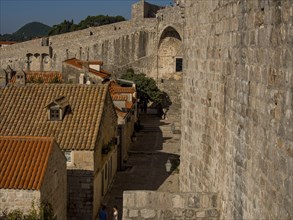 A narrow alley along a city wall with old houses and red roofs, dubrovnik, Mediterranean Sea,