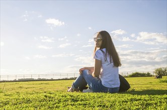 Young woman sitting on the grass with a protective mask during the SARS CoV-2 pandemic season