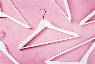 Fashion collection concept. White wooden hangers, a flat lay layout on pink. Shopping background,