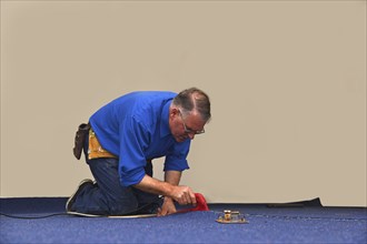 A floorlayer uses a hot iron to seal the glue strip in a join a new carpet