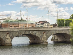 Stone bridge over a river in a city with historic buildings and blue sky with clouds, stockholm,