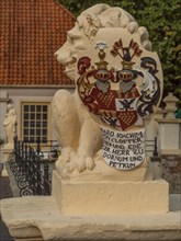 Close-up of a lion statue with coat of arms in the foreground, dornum, east frisia, germany