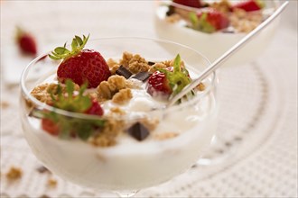 Close up of dessert with strawberries cereals chocolate flakes and yogurt