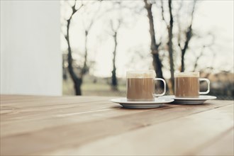 Two cups of coffee in the wooden brown terrace background.