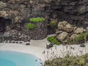 Small, isolated oasis with turquoise water, surrounded by rocks and lush vegetation, Lanzarote,