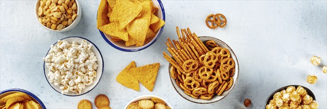 Salty snacks, party mix panorama, shot from the top. An assortment of appetizers, a flat lay.