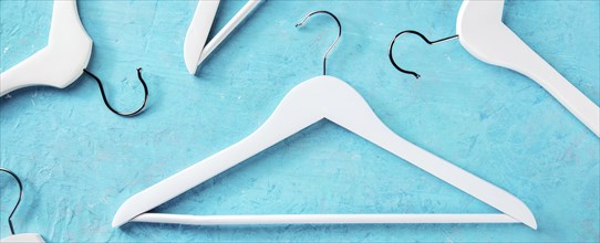 Fashion collection panorama. White wooden hangers, a flat lay layout on blue. Shopping background,