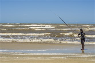 Young man fishing on beach, sport fishing