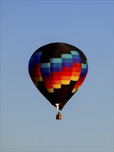 A colorful hot air balloon shooting a flame floats in the sky in north Idaho