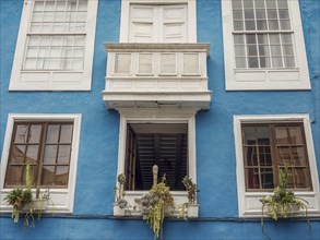 Close-up of a blue house with white windows and a decorative balcony with plants, la palma, canary