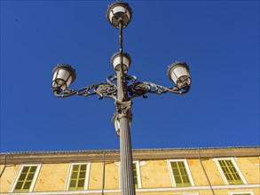 High, decorative street lamp against a clear blue sky in front of a building, palma de Majorca,