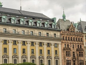 Colourful historic buildings with different roof styles and many windows under a grey sky,