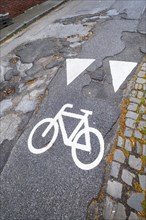 A cycle path pictogram on a road with potholes in Mönchengladbach, Germany, Europe