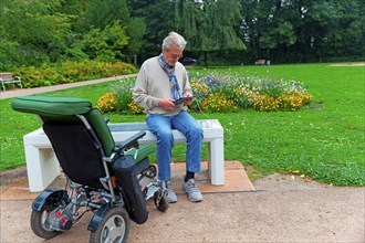 Man sits on a Smart Bensh and charges his Ipad, modern technology, bench with solar panel and