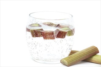 Transparent glass filled with cold water and several pieces of rhubarb isolated on white background