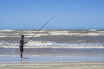 Young man fishing on beach, sport fishing