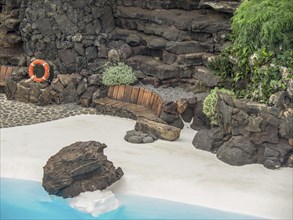 White sand with rocks, a blue pool, bench and lifebuoy, lanzarote, Canary Islands, Spain, Europe