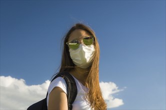 Girl wearing Mouth and nose protection mask looking at camera on sunny day