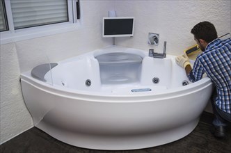 Installation of modern bath, (hot tub), applying sealant, bathtub with tv