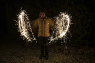 A child paints circles of light with sparklers