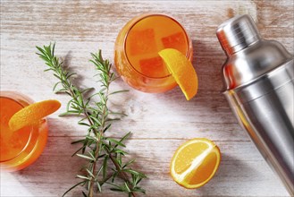 Orange cocktails with rosemary and a shaker, shot from the top on a wooden background, Food