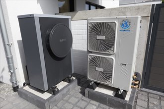 Outdoor units of an air-to-water heat pump in front of a newly built two-family house, heating and