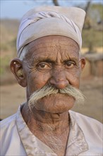 Herdsman from the tribe of the Maldhari in a typical white robe and golden earrings, portrait, Gir