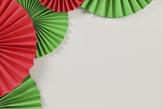 Red and Green paper craft rosettes in traditional Christmas colors on side of gray background with