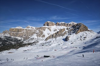 View of a ski resort piste with people skiing in Dolomites in Italy. Ski area Belvedere. Canazei,