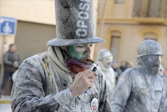 Man lighting firecracker with a cigar, Els Enfarinats flour fight, rebels, armed with flour, eggs