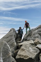 Male and female climbers high-fiving at the top of the mountain. Mixed rock climbing team