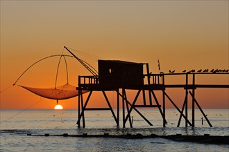 Traditional carrelet fishing hut with lifting net on the beach at sunset, Loire-Atlantique,