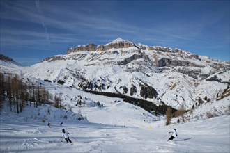 View of a ski resort piste with people skiing in Dolomites in Italy. Ski area Arabba. Arabba,