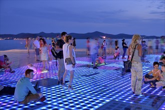 People at the Monument to the Sun, Pozdrav Suncu, by architect Nikole Bašica, at dusk, Zadar,